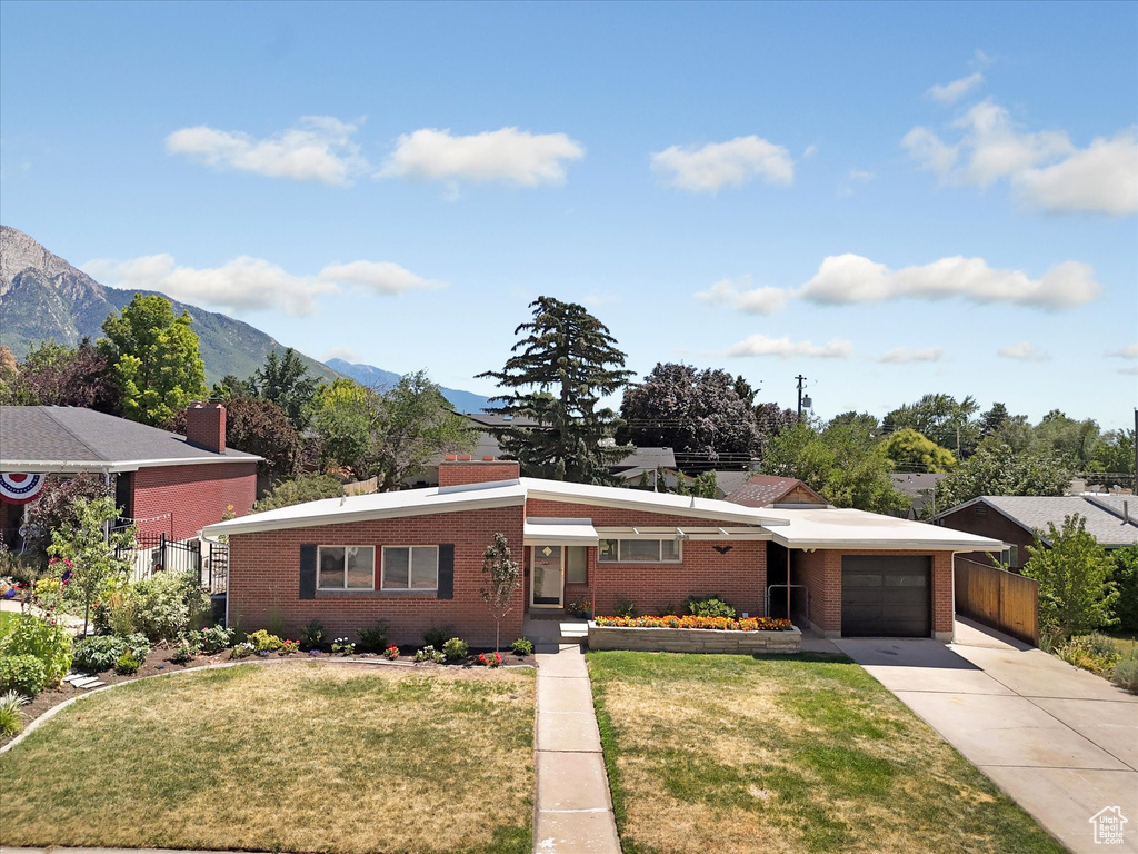 View of front facade with a garage, brick siding, concrete driveway, and a mountain view