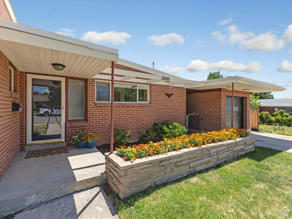 Property entrance featuring brick siding and a lawn