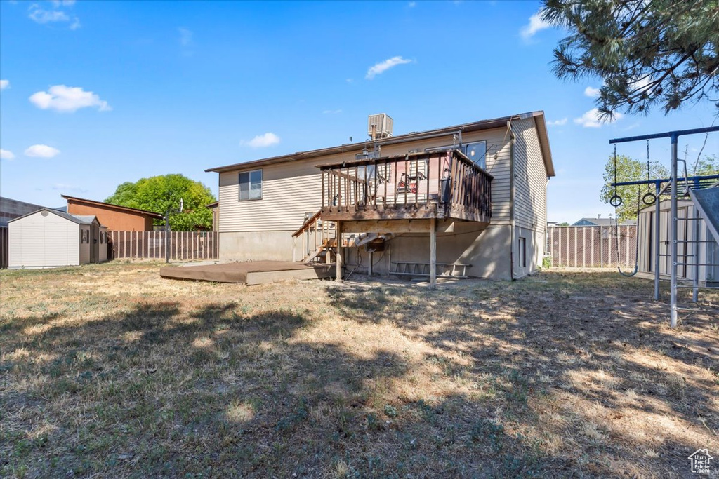 Back of property with a storage shed, a fenced backyard, a wooden deck, and a patio area