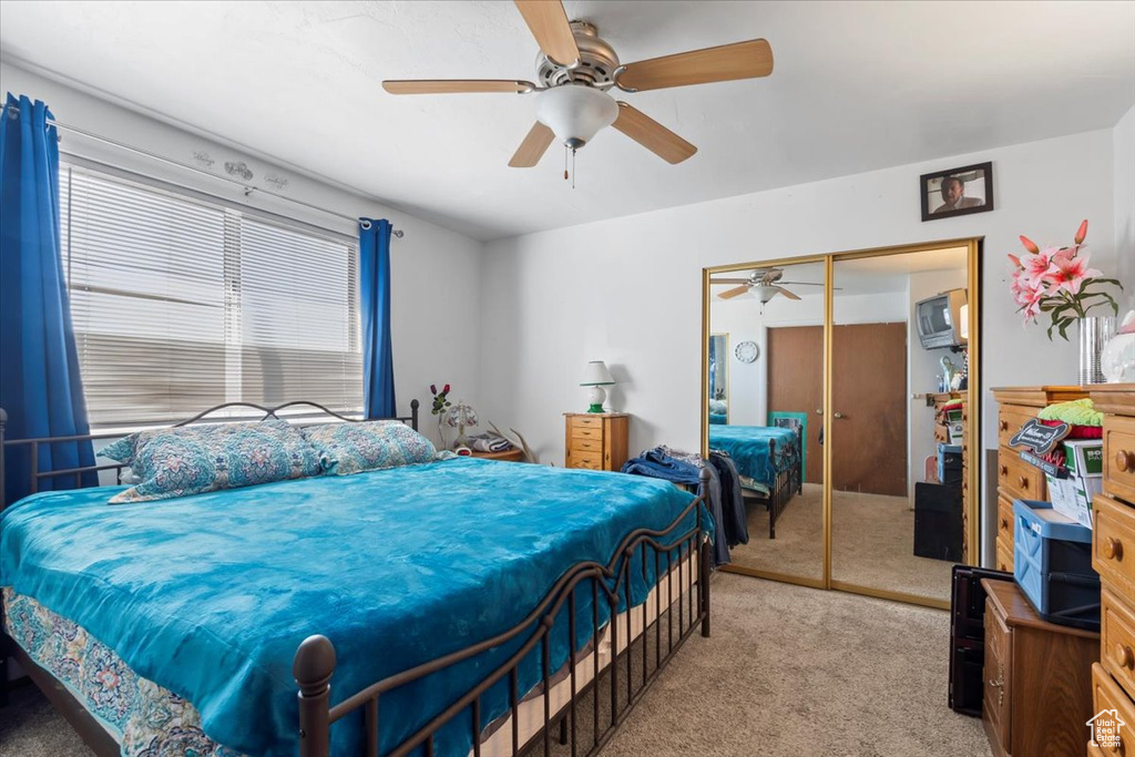 Bedroom with light carpet, a closet, and a ceiling fan