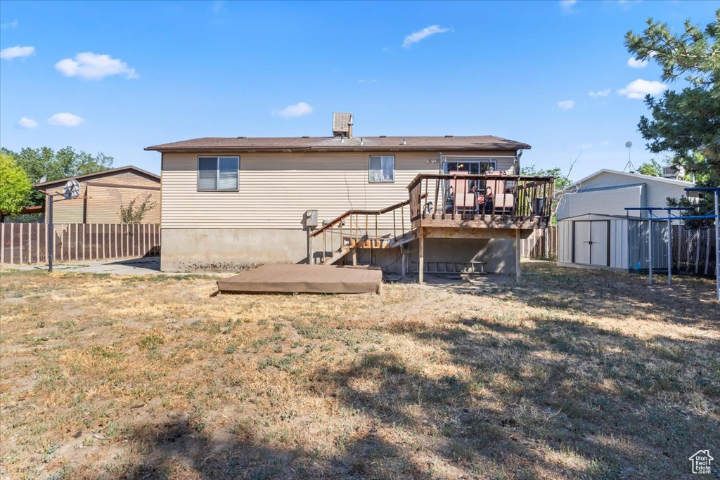 Rear view of house with a shed, a wooden deck, and stairs