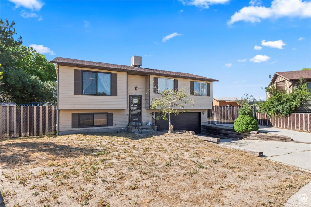 Split foyer home with a garage, driveway, and entry steps