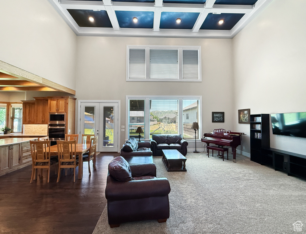 Living room featuring a towering ceiling, french doors, coffered ceiling, beamed ceiling, and ornamental molding