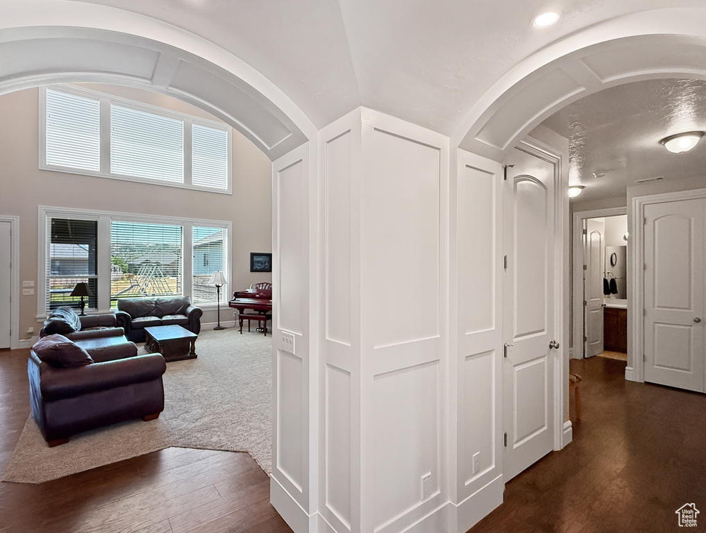 Hallway featuring arched walkways and dark wood-type flooring