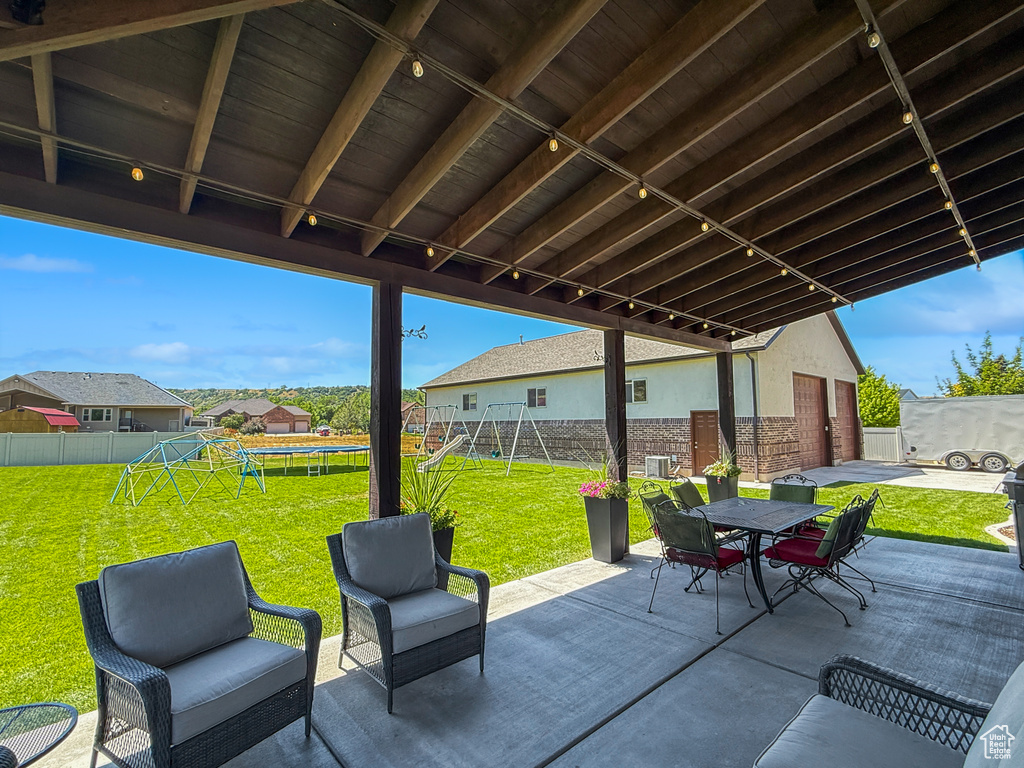 Fenced backyard featuring a playground, a patio, a trampoline, and outdoor dining area