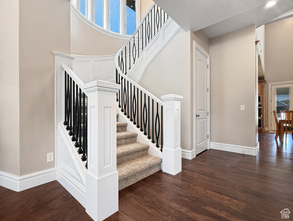 Stairway featuring wood finished floors and a towering ceiling