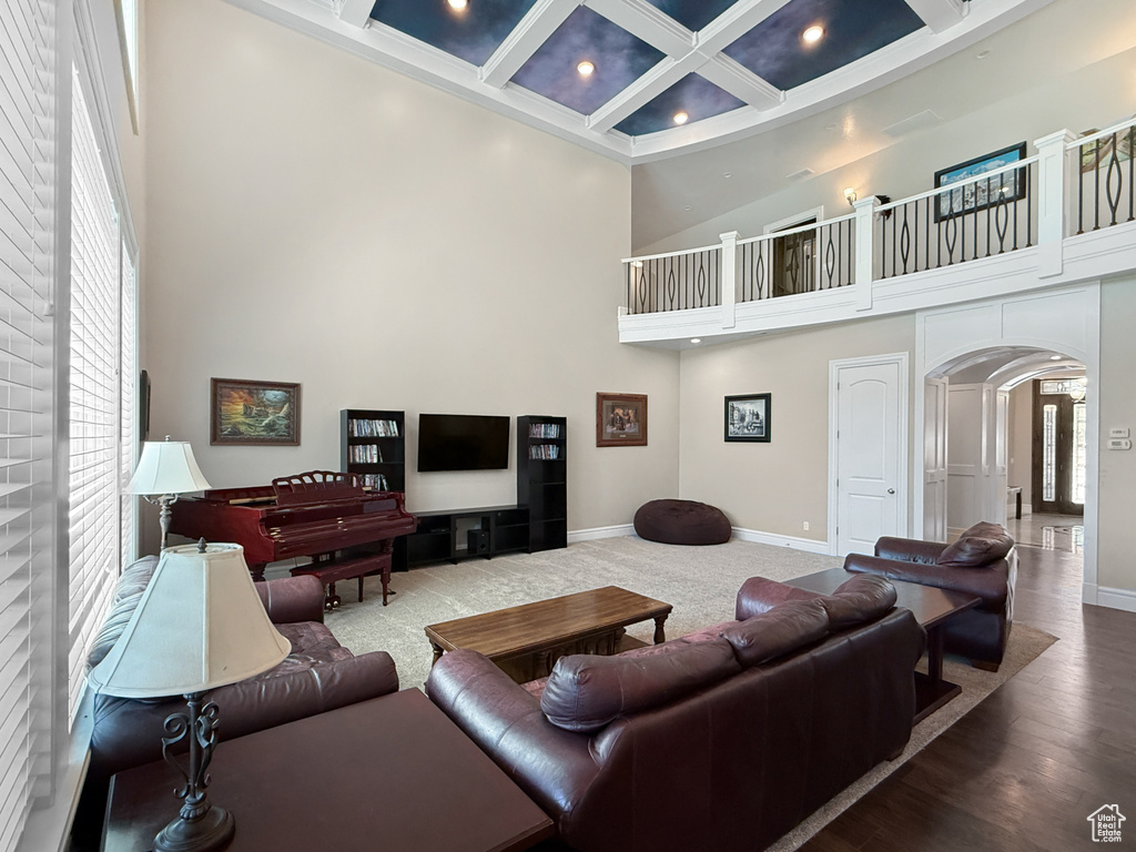 Living area featuring a towering ceiling, plenty of natural light, arched walkways, recessed lighting, and coffered ceiling