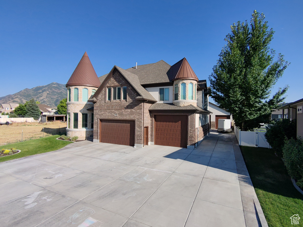 View of front of home with a garage, a standing seam roof, brick siding, a metal roof, and driveway