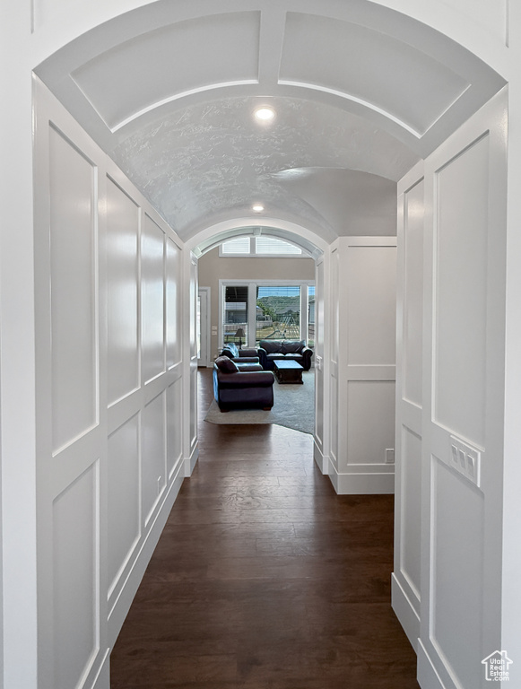 Corridor featuring lofted ceiling, dark wood finished floors, arched walkways, and recessed lighting