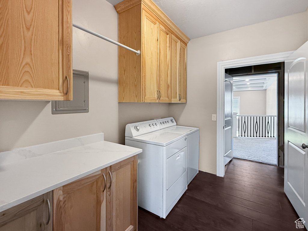 Washroom with cabinet space, dark wood-style floors, electric panel, and washing machine and dryer