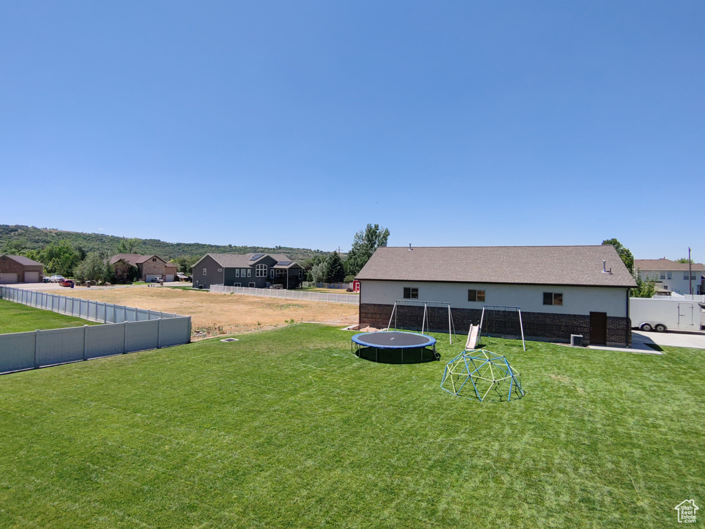 Fenced backyard featuring a trampoline