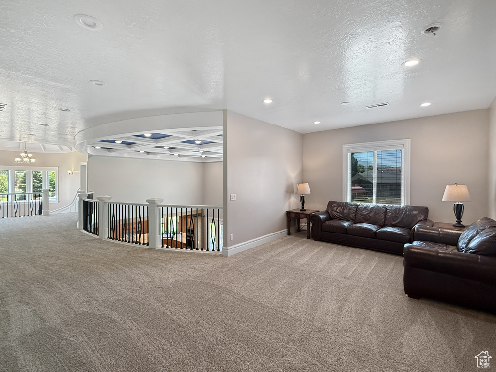 Carpeted living area with a chandelier, a textured ceiling, and recessed lighting
