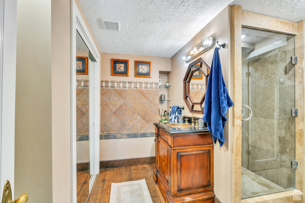 Full bathroom featuring hardwood / wood-style flooring, vanity, a textured ceiling, and a shower stall