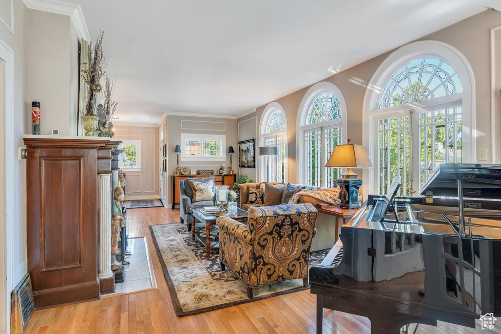Living area with plenty of natural light, light wood-style floors, and ornamental molding