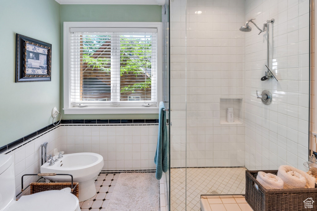 Full bath with a stall shower, a bidet, tile walls, and wainscoting