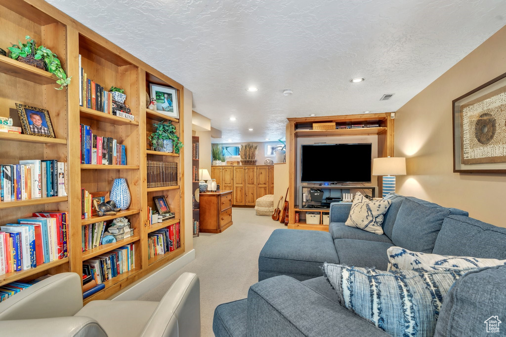 Carpeted living room with recessed lighting and a textured ceiling