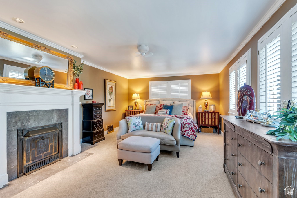 Bedroom with light colored carpet, ornamental molding, and a fireplace