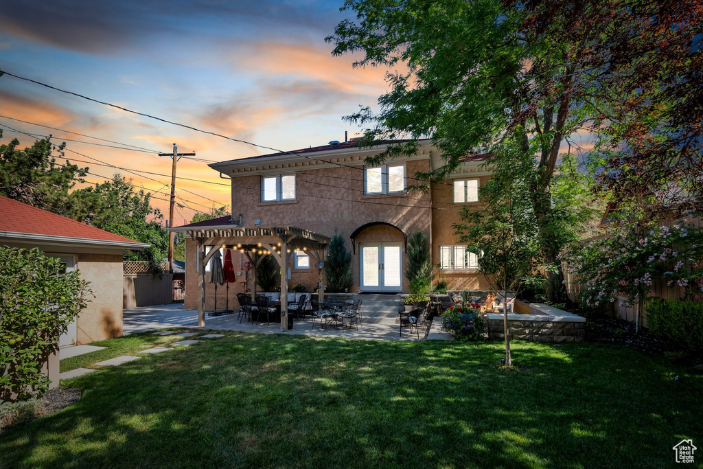 Back of property at dusk with a pergola, a patio, french doors, and stucco siding