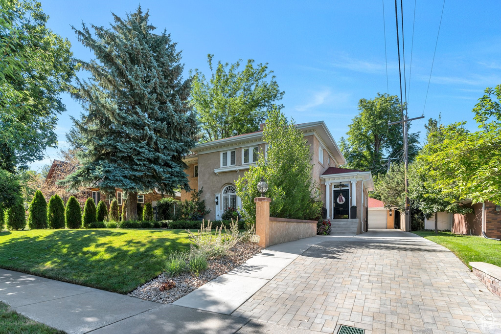 View of front facade with decorative driveway, stucco siding, and a front yard