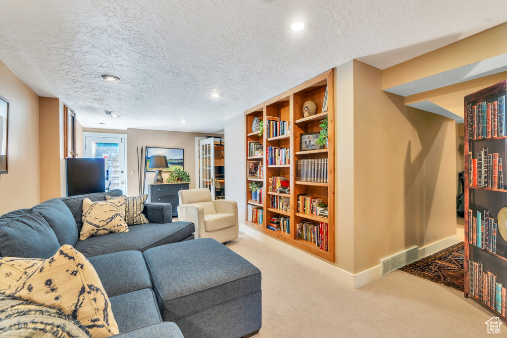 Carpeted living area with a textured ceiling and recessed lighting