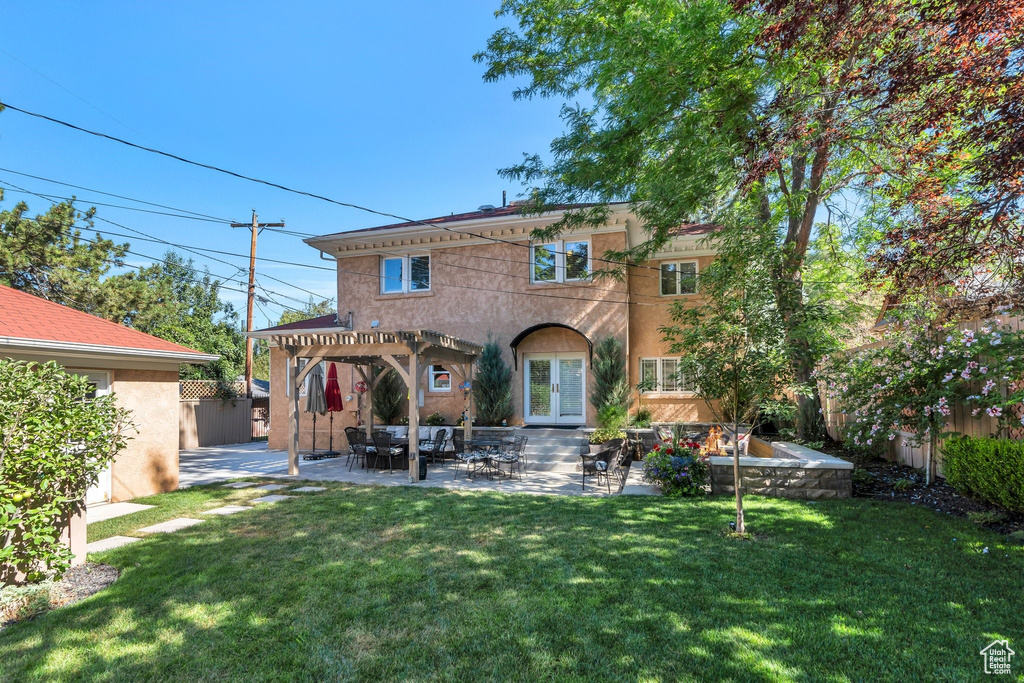 Rear view of property featuring a pergola, a patio, stucco siding, and french doors