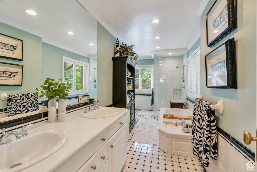 Bathroom featuring a bath, double vanity, a stall shower, ornamental molding, and recessed lighting
