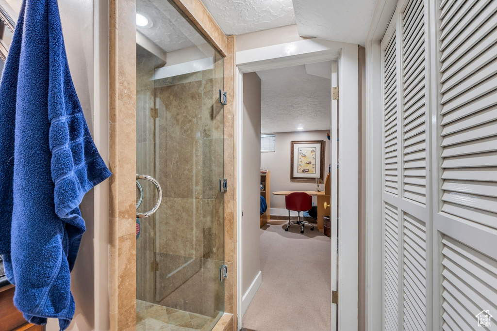 Bathroom featuring a shower stall, a textured ceiling, and a closet