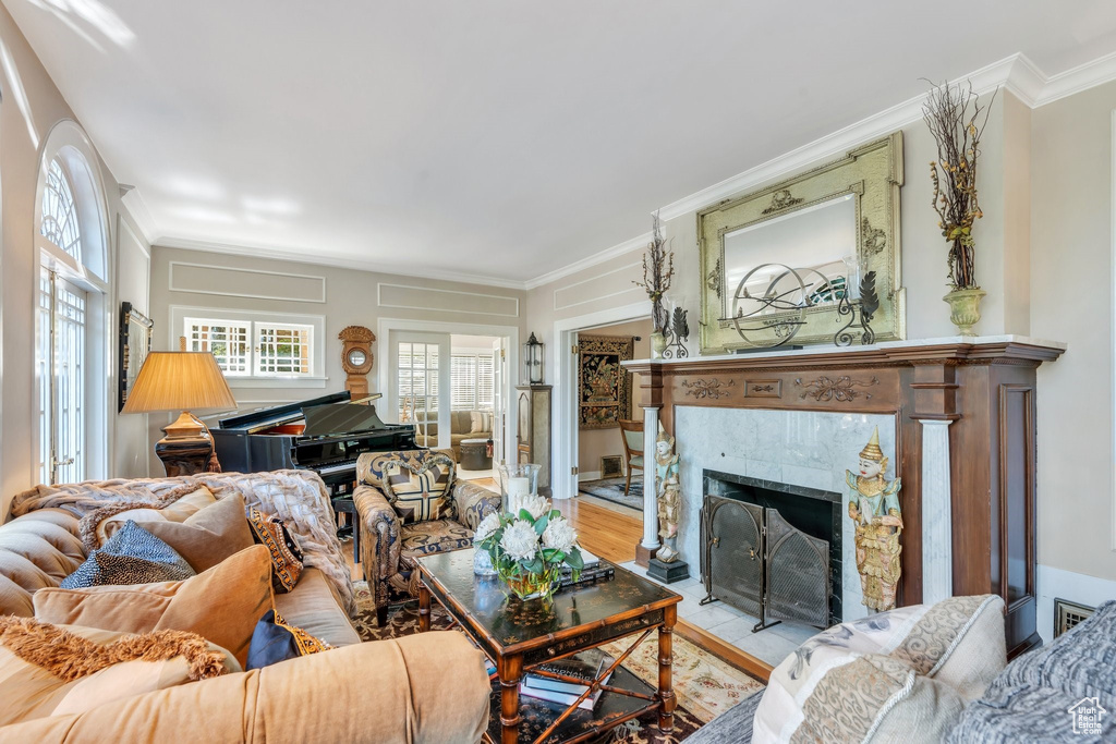 Living area with crown molding, plenty of natural light, a tile fireplace, and wood finished floors