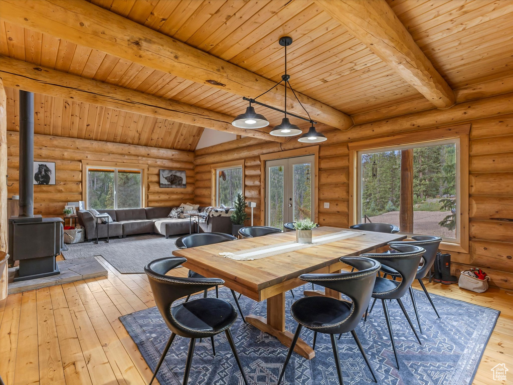 Dining space featuring log walls, a wood stove, hardwood / wood-style flooring, french doors, and a wood ceiling with exposed beams