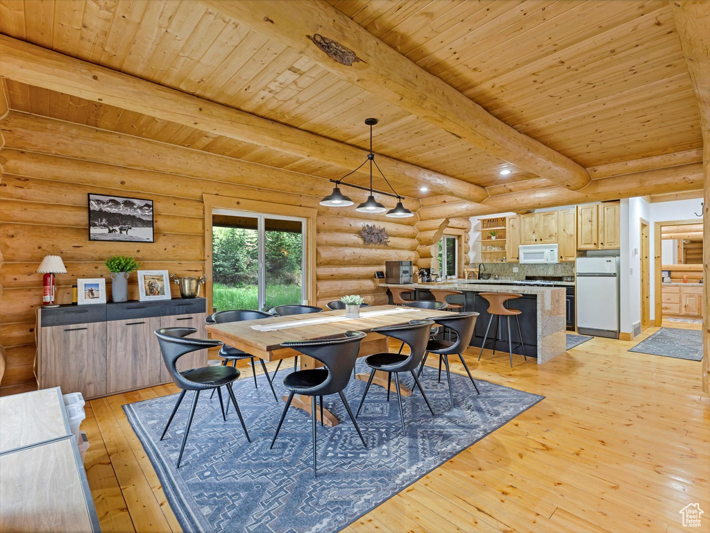 Dining area with rustic walls, a wooden ceiling with exposed beams, and light wood-style flooring