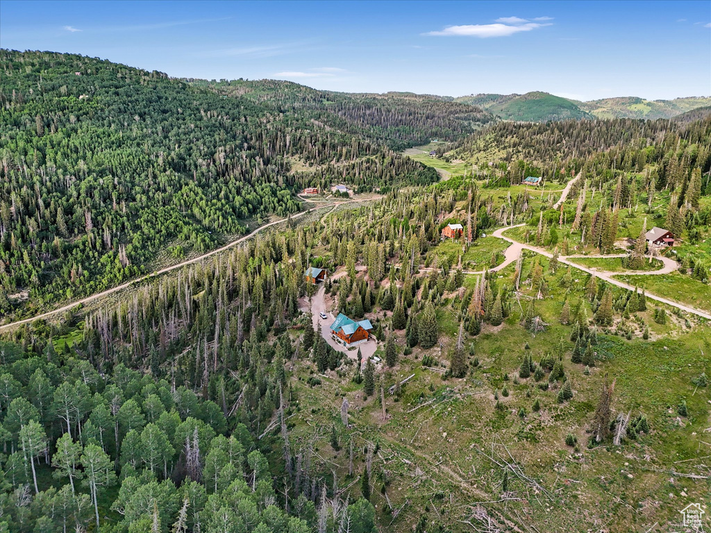 Aerial view of property and surrounding area featuring a forest and a mountain backdrop