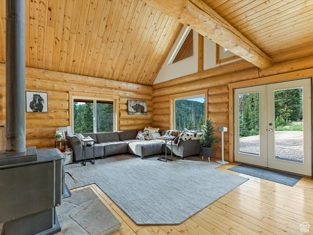 Living area featuring a wood stove, a wood ceiling with exposed beams, french doors, log walls, and high vaulted ceiling
