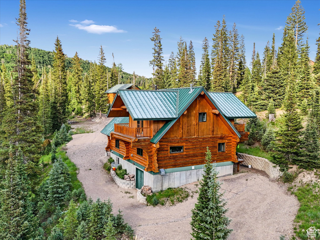 View of home\\\\\\\\\\\\\\\\\\\\\\\\\\\\\\\\\\\\\\\\\\\\\\\\\\\\\\\\\\\\\\\'s exterior with log siding, a balcony, dirt driveway, a forest view, and a standing seam roof