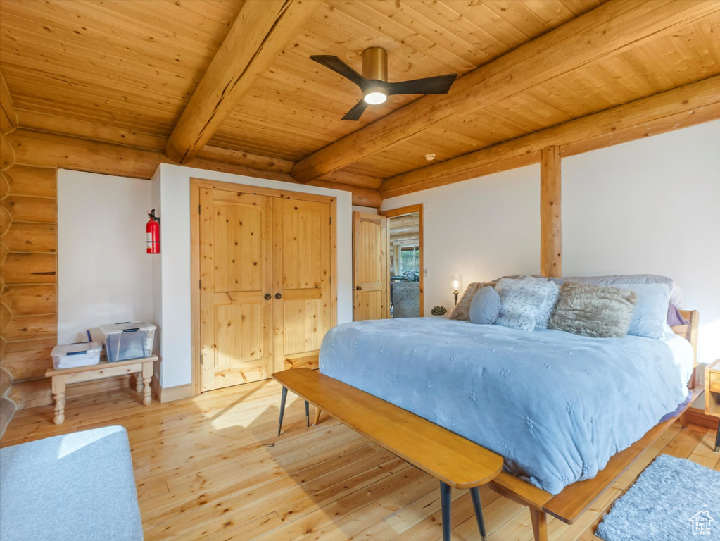Bedroom featuring rustic walls, a wood ceiling with exposed beams, and light wood finished floors