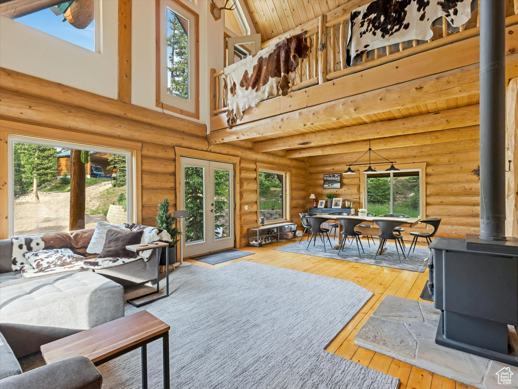 Living room featuring a wood stove, log walls, wood-type flooring, a towering ceiling, and wood ceiling