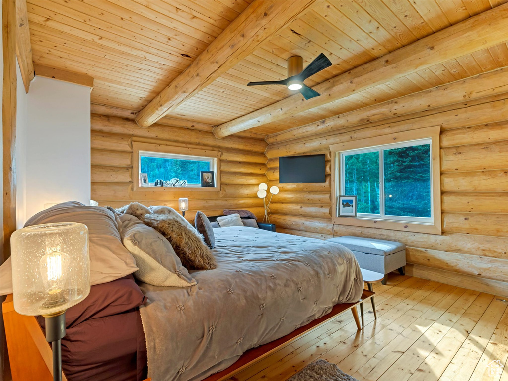 Bedroom featuring rustic walls, hardwood / wood-style floors, a wood ceiling with exposed beams, and multiple windows