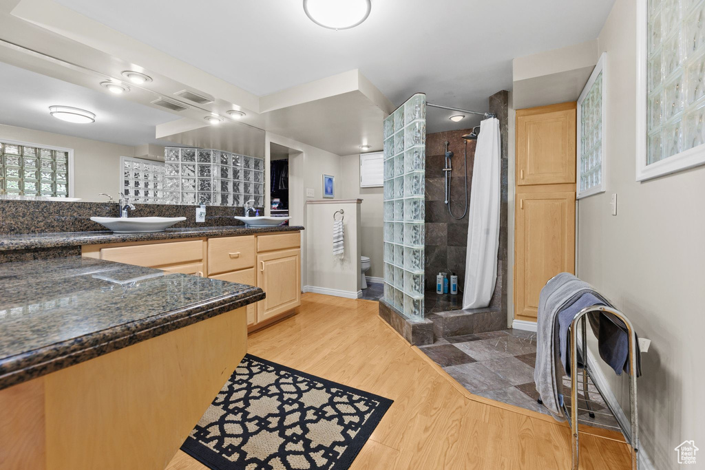 Full bathroom featuring a shower stall, double vanity, and wood finished floors