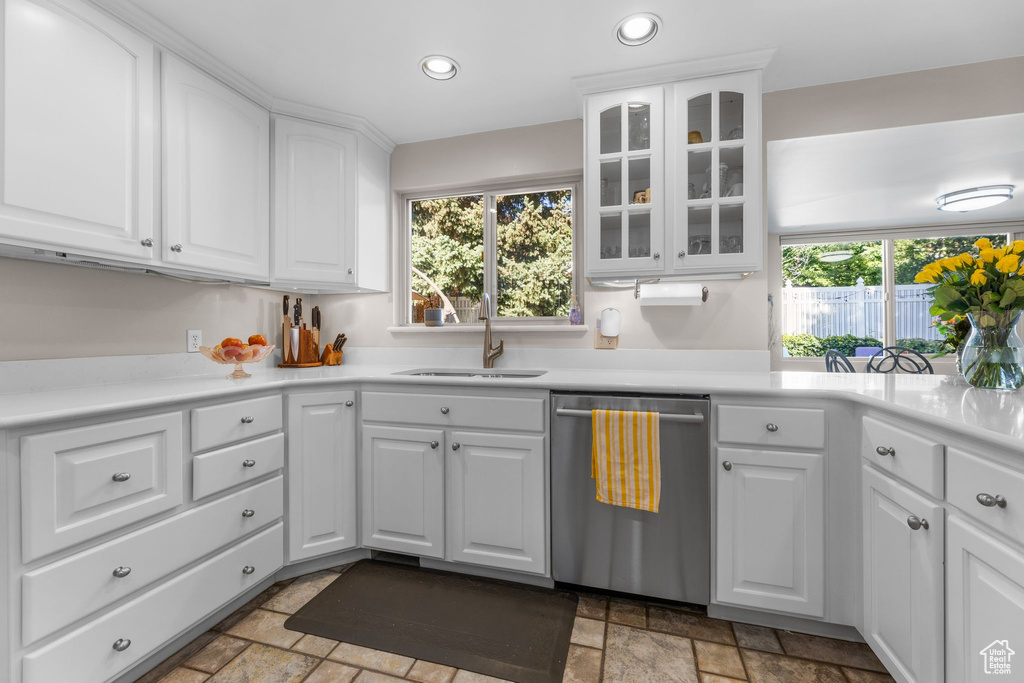 Kitchen featuring dishwasher, stone tile floors, recessed lighting, glass insert cabinets, and white cabinetry