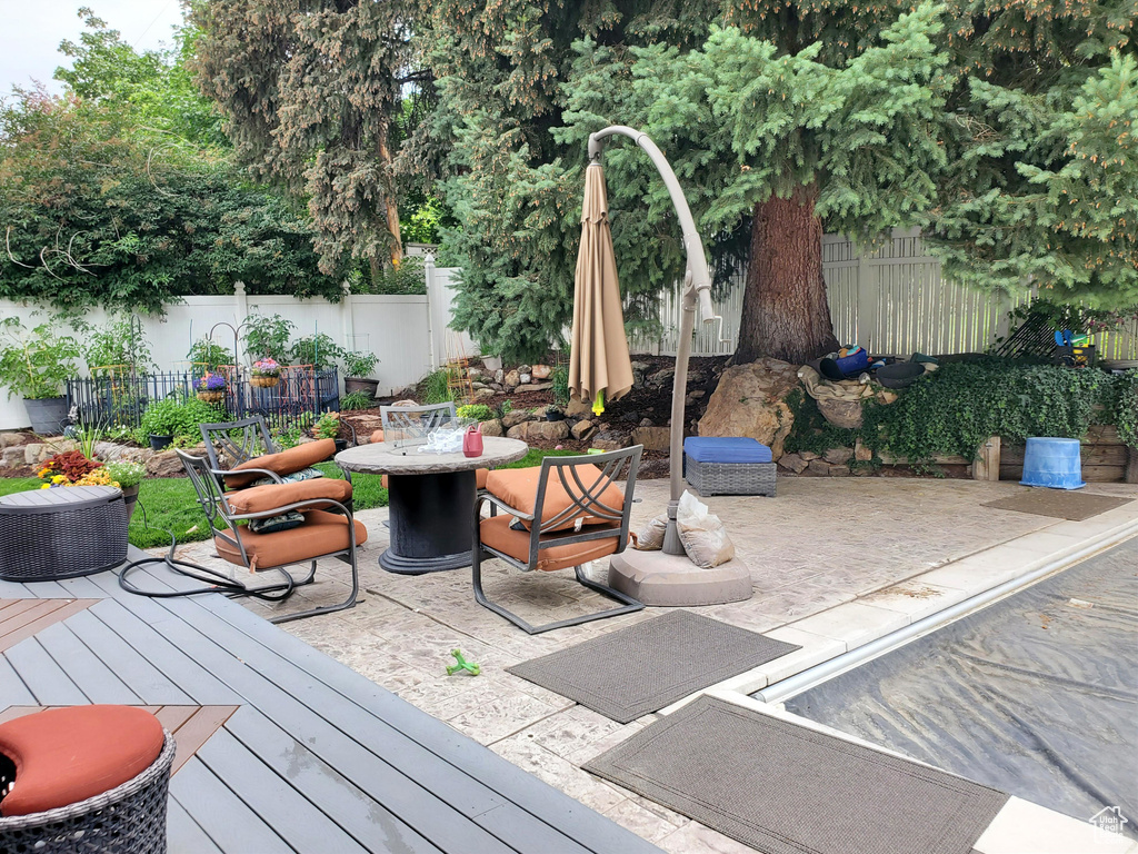 Deck with outdoor dining space, a fenced backyard, and a patio