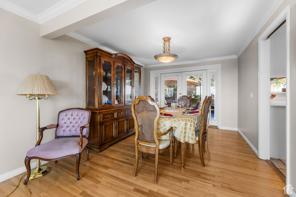 Dining space featuring french doors, ornamental molding, and light wood-type flooring