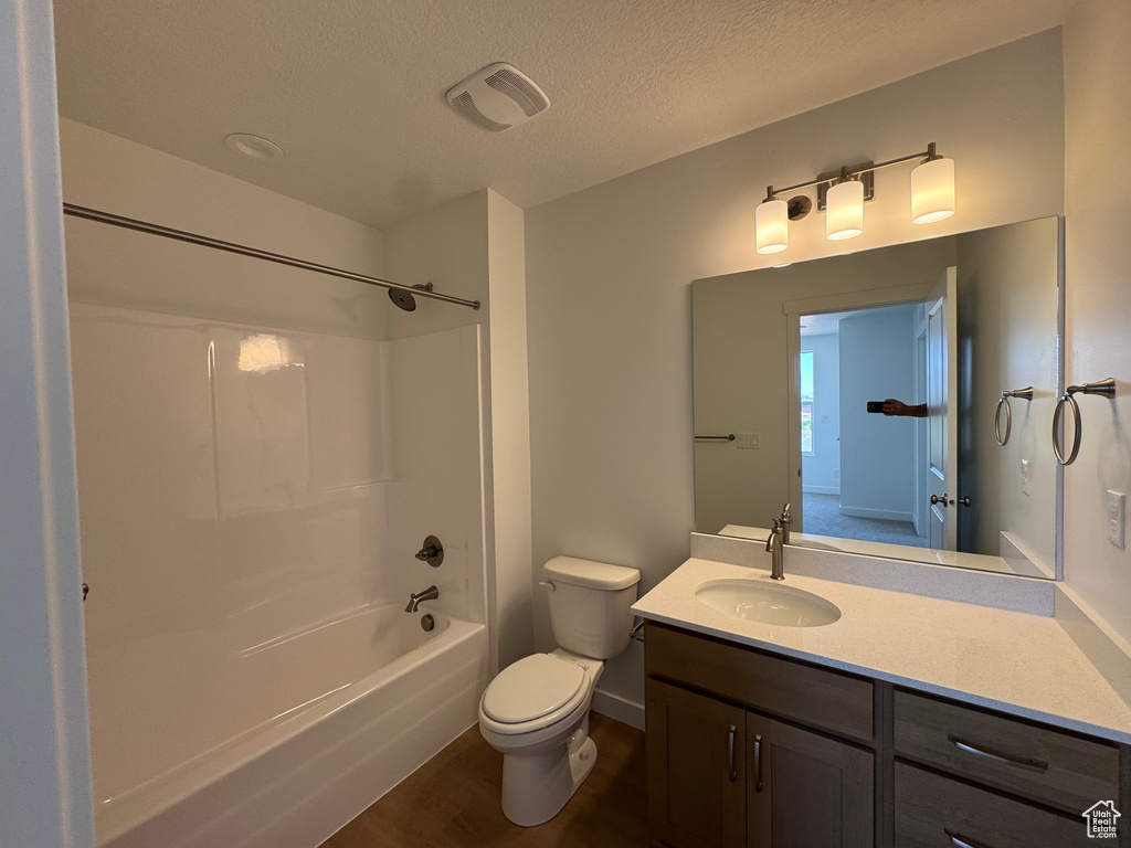 Full bath with wood finished floors, vanity, washtub / shower combination, and a textured ceiling