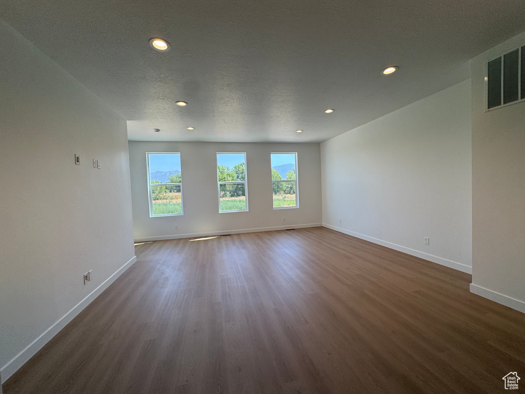 Empty room with dark wood-style floors and recessed lighting