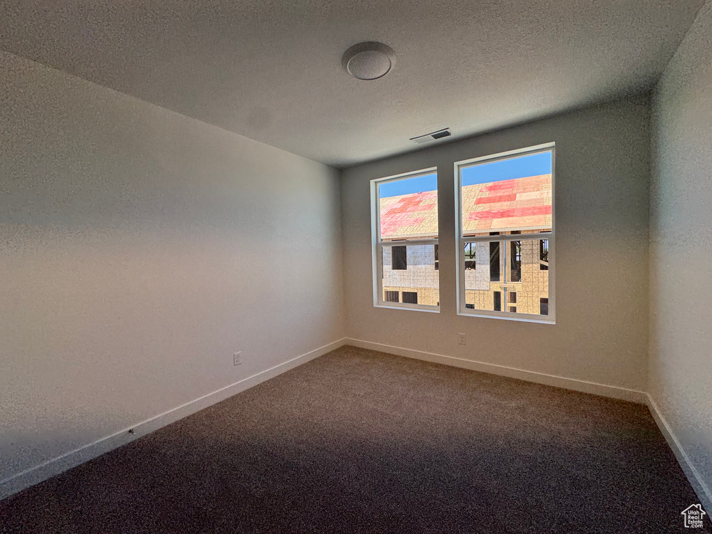 Spare room with dark colored carpet and a textured ceiling