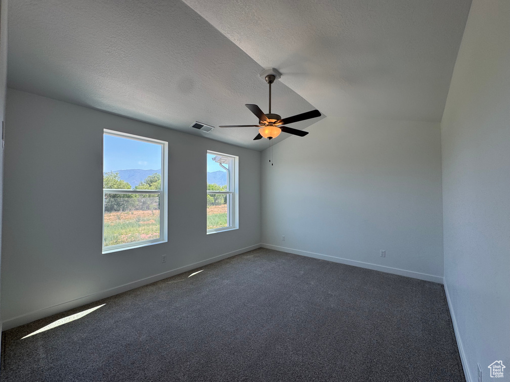 Unfurnished room with a ceiling fan, dark carpet, a textured ceiling, and lofted ceiling