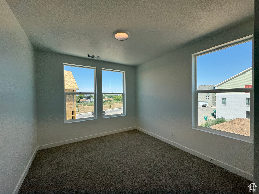 Spare room featuring a textured ceiling and dark carpet
