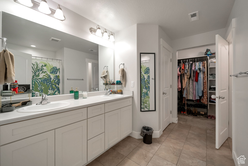 Bathroom featuring double vanity, a walk in closet, and tile patterned floors