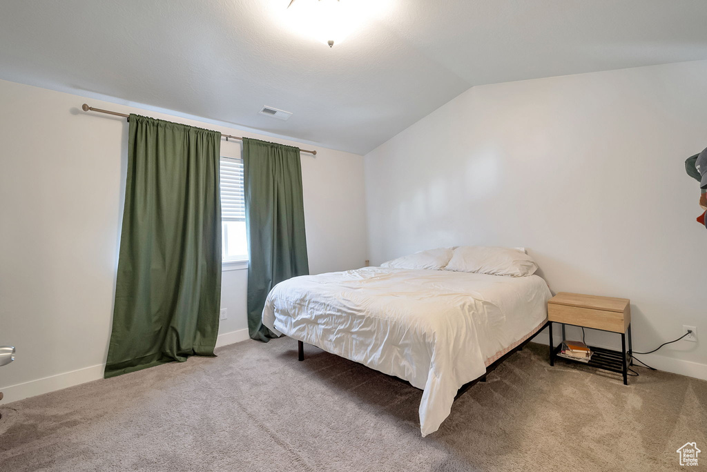 Bedroom with vaulted ceiling and carpet