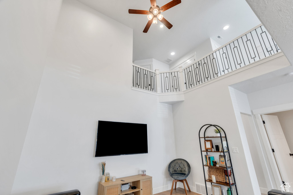 Living area with ceiling fan, a high ceiling, and recessed lighting