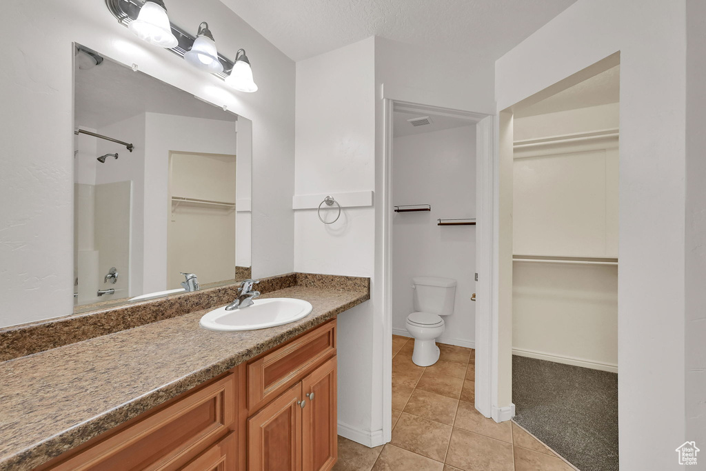 Full bath with vanity, tile patterned flooring, a walk in closet, and a shower