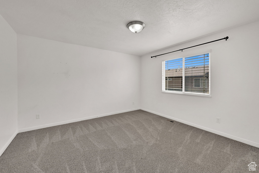 Carpeted empty room with baseboards and a textured ceiling
